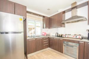eine Küche mit Holzschränken und einem Edelstahlkühlschrank in der Unterkunft Sea blue pool villa in Bang Lamung