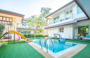 einen Hinterhof mit Pool mit Rutsche und Spielplatz in der Unterkunft Sea blue pool villa in Bang Lamung