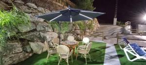a table with chairs and an umbrella on the grass at La Casona del Pinar Swiming Pool in Alhaurín de la Torre