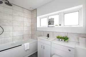 a white bathroom with a sink and a bath tub at Skyvillion - STEVENAGE SPACIOUS & COZY 3Bed House with Parking, Wifi, Garden in Aston End +19 photos