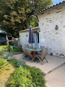 a table and chairs with an umbrella on a patio at le Domaine du Petit Bois, Gîte le Marronnier in Varzay +9 photos