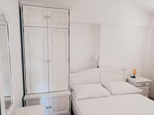 a white bedroom with a white cabinet and a bed at Apartments Jurjevic in Petrcane
