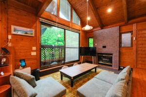 a living room with a couch and a table and a fireplace at Kurokawa Mori No Kiki in Minamioguni
