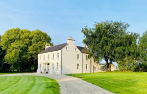 a large white house on a grassy field at Meathpark Country House in Coleraine