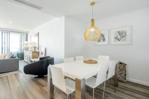 a white dining room with a white table and chairs at Absolute Kirra by EcoTime in Gold Coast