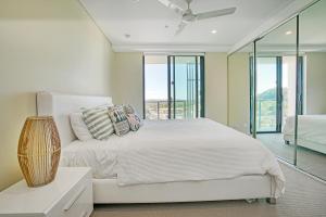 a bedroom with a white bed and glass windows at Absolute Kirra by EcoTime in Gold Coast +16 photos