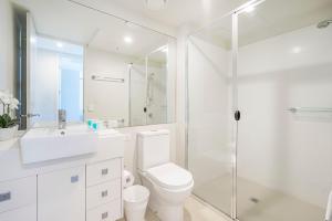 a white bathroom with a toilet and a shower at Absolute Kirra by EcoTime in Gold Coast