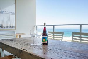 a bottle of wine sitting on a wooden table with two glasses at Absolute Kirra by EcoTime in Gold Coast