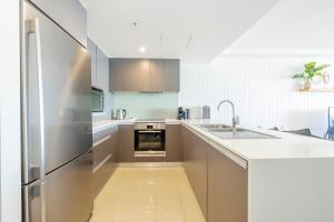 a kitchen with a stainless steel refrigerator and a sink at Absolute Kirra by EcoTime in Gold Coast