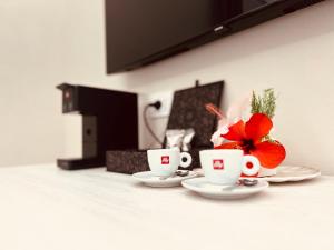 two coffee cups and a red flower on a table at Maison Madeleine in La Maddalena