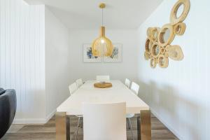 a white dining room with a white table and chairs at Absolute Kirra by EcoTime in Gold Coast