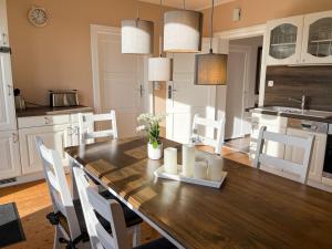 a kitchen with a wooden table with white chairs at Ferienwohnung auf dem Alpaka-Hof in Rubkow