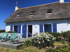a house with two chairs and a thatched roof at Longère - 10 personnes - Vue mer in Tréguennec