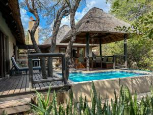 a house with a swimming pool and a thatch roof at Hoedspruit Raptors Lodge N16 in Hoedspruit