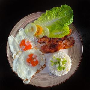 a plate of food with eggs bacon lettuce and rice at Mojo Hostel in Puerto Princesa City
