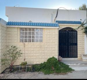 a yellow brick building with a black door at Maison independante taourit in Houmt Souk