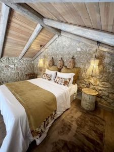 a bedroom with a bed and a stone wall at Selene Luxury Rooms in Sinevrón