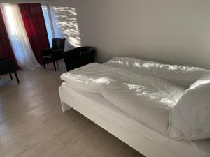 a white bed in a room with chairs at Dream Vacation for 4 Geusts easy to arrive in Spiez