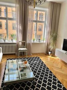 a living room with a glass table in a room with windows at Modern lägenhet med balkong in Stockholm