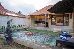 a pool in the yard of a house with a fountain at Soka Villa in Ubud