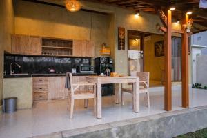 a kitchen with a wooden table and some chairs at Soka Villa in Ubud