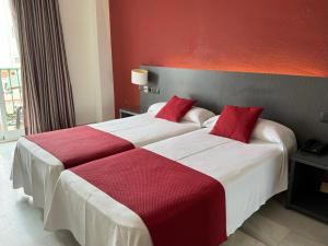 two beds in a hotel room with red walls at Hotel Nerja Club by Dorobe in Nerja