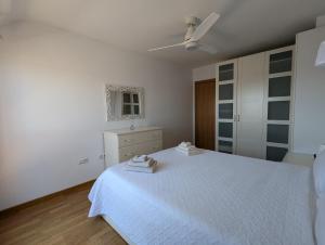 a white bedroom with a bed and a ceiling fan at Puerta del Noroeste in Benavente