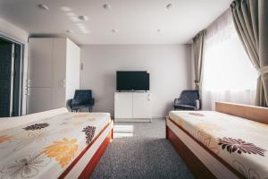 a hotel room with two beds and a flat screen tv at Mingės Egzotika in Mingė