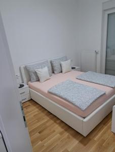 a bedroom with a bed with pink sheets and pillows at Apartman San in Posušje