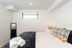 a bedroom with a bed with two towels on it at Stellar Central City Apartment - Hagley Park in Christchurch