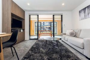 a living room with a couch and a table at Stellar Central City Apartment - Hagley Park in Christchurch