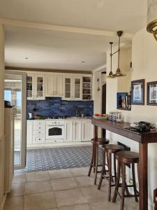 a kitchen with white cabinets and a island with bar stools at Villa on Luštica peninsula with fantastic sea view in Mitrovići