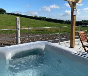 a hot tub with a chair and a fence at The Byre at Conker Tree Cottages in Saintfield