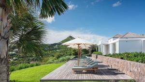a group of lounge chairs and an umbrella at Ideally located Prestigious Villa in Toiny
