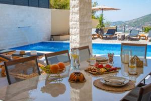 a table with food on it next to a swimming pool at NEW! Casa Vita featuring a sea view, billiards, and heated pool in Omiš