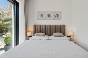 a white bed with two pillows in a bedroom with a window at NEW! Casa Vita featuring a sea view, billiards, and heated pool in Omiš +52 photos