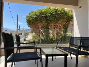 three chairs and a table on a balcony with a palm tree at M P A Luxury Apartment Α2 in Agios Nikolaos