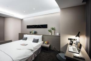 a bedroom with a bed and a desk with a laptop at Hotel Reve Taichung in Daya