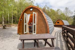 a wooden iguana cabin with a bench and a table at Cosy Glamping In the Eskdale Valley - Studio Lodges and Mega Pods in Eskdale
