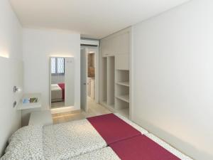 a bedroom with a white bed and a red rug at Apartaments Ses Dàlies in Port d'Alcudia