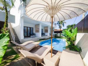 a patio with chairs and an umbrella next to a swimming pool at Cannella Suites Ubud - Ubud Center prime location in Ubud
