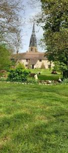 a church with a tower and a field of grass at La ferme du Baume, Loiret in Beaune-la-Rolande
