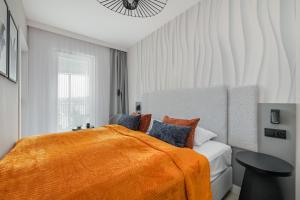 a bedroom with a bed with an orange blanket at Apartament Baltic Waves Basen Siłownia Sauna by Rent like home in Międzyzdroje