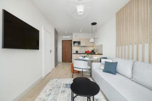 a living room with a couch and a tv on a wall at Apartament Baltic Waves Basen Siłownia Sauna by Rent like home in Międzyzdroje