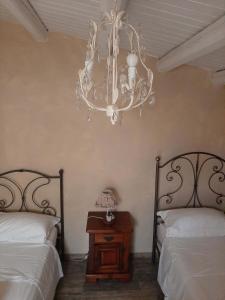 a bedroom with two beds and a chandelier at La Casa Di Piero e Mary in Brucoli