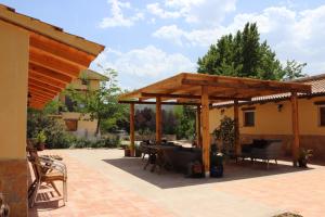un patio con una pérgola de madera con mesas y sillas en Physionatural B&B, en Mas de las Matas