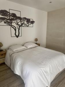 a bedroom with a white bed with a tree picture on the wall at Cozy Caze in Saint-Joseph