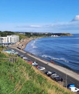 a line of cars parked on a road next to the ocean at Inspiro house4 in Scarborough