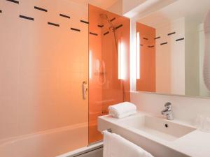La salle de bains est pourvue d'une baignoire, d'un lavabo et d'un miroir. dans l'établissement ibis Styles Paris Bercy, à Paris