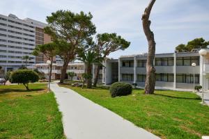 una acera frente a un edificio con árboles en AluaSun Cala Antena - All Inclusive, en Calas de Mallorca